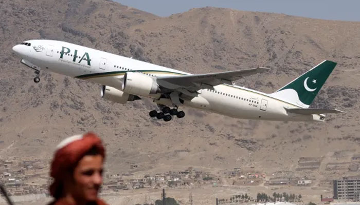 A Taliban fighter stands guard as a PIA aircraft takes off with passengers on board at the airport in Kabul. — AFP/File