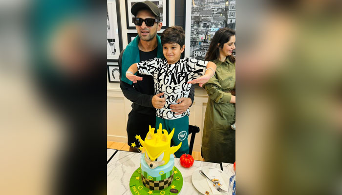 Former Pakistan captain Shoaib Malik poses for a photograph with his son Izhaan and Indian tennis star Sania Mirza is seen standing behind them. — X/@realshoaibmalik