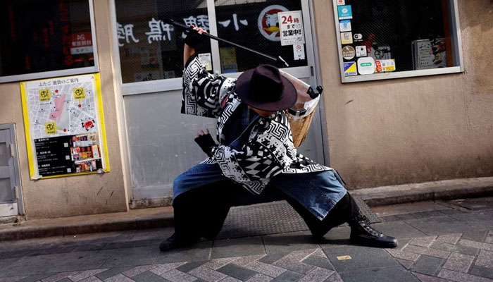 Keisuke Naka, a members of Gomihiroi Samurai (trash-picking samurai) clad in denim yukata, picks up trash on the street of Ikebukuro in the morning after Halloween while he performs samurai sword fighting by using their fire scissors in Tokyo, Japan November 1, 2023. —Reuters