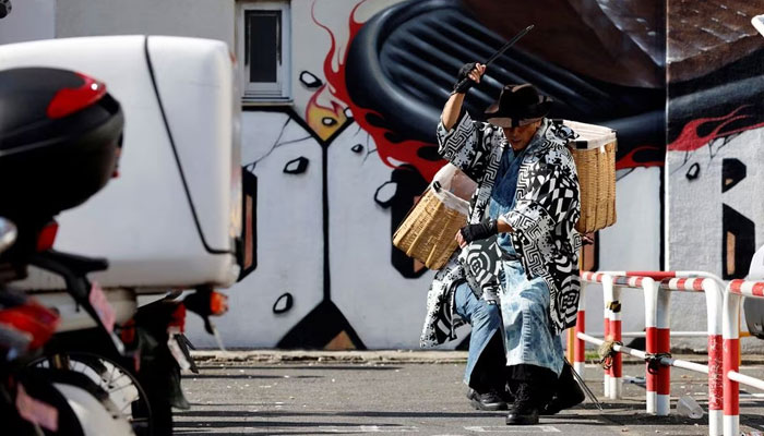 Keisuke Naka and Ikki Goto, members of Gomihiroi Samurai (trash-picking samurai) clad in denim yukata, pick up trash at a parking lot of Ikebukuro in the morning after Halloween while they perform samurai sword fighting by using their fire scissors in Tokyo, Japan November 1, 2023. —Reuters