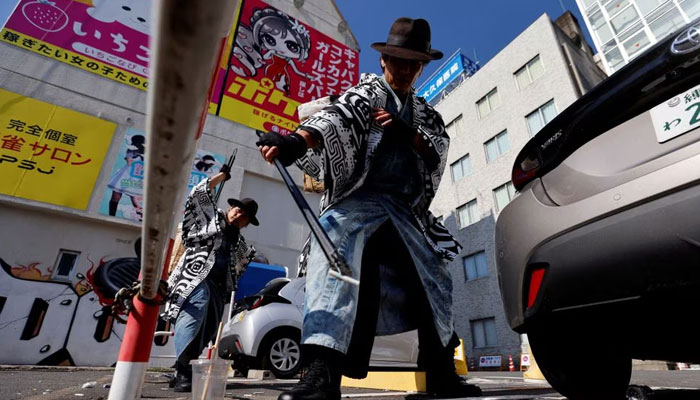 Keisuke Naka and Ikki Goto, members of Gomihiroi Samurai (trash-picking samurai) clad in denim yukata, pick up trash at a parking lot of Ikebukuro in the morning after Halloween while they perform samurai sword fighting by using their fire scissors in Tokyo, Japan November 1, 2023.— Reuters