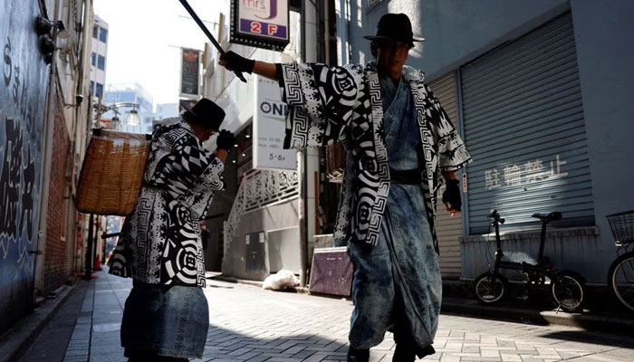 Keisuke Naka and Ikki Goto, members of Gomihiroi Samurai (trash-picking samurai) clad in denim yukata, pick up trash on the streets of Ikebukuro in the morning after Halloween while they perform samurai sword fighting by using their fire scissors in Tokyo, Japan November 1, 2023. — Reuters