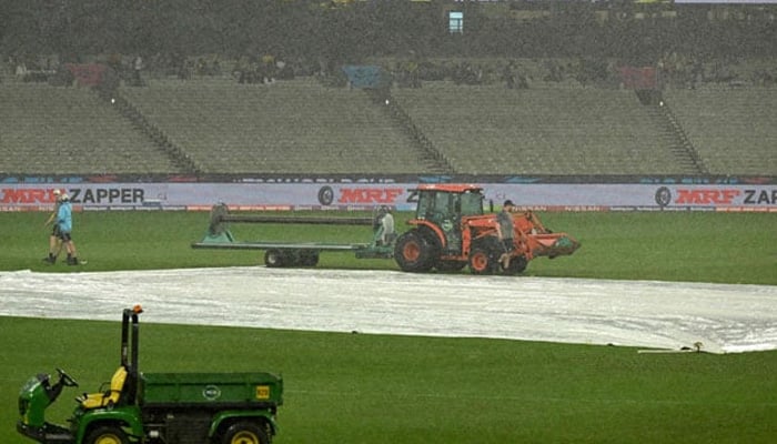 Ground staff cover the field as rain delays the start of play during the ICC mens T20 World Cup 2022 cricket match between New Zealand and Afghanistan and Ireland at Melbourne Cricket Ground (MCG) on October 26, 2022 in Melbourne. — AFP