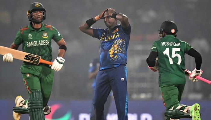 Bangladeshs Mahmudullah (L) and Mushfiqur Rahim run between the wickets as Sri Lankas Angelo Mathews (C) watches during the 2023 ICC Mens Cricket World Cup one-day international (ODI) match between Bangladesh and Sri Lanka at the Arun Jaitley Stadium in New Delhi on November 6, 2023. — AFP
