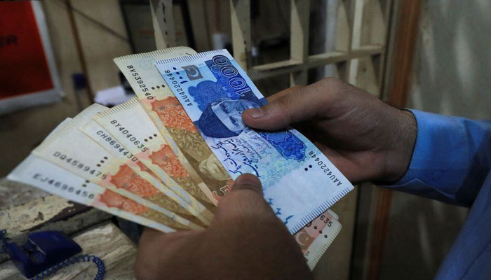 A man counts Pakistani rupee notes at a currency exchange shop in Peshawar, Pakistan September 12, 2023. — Reuters