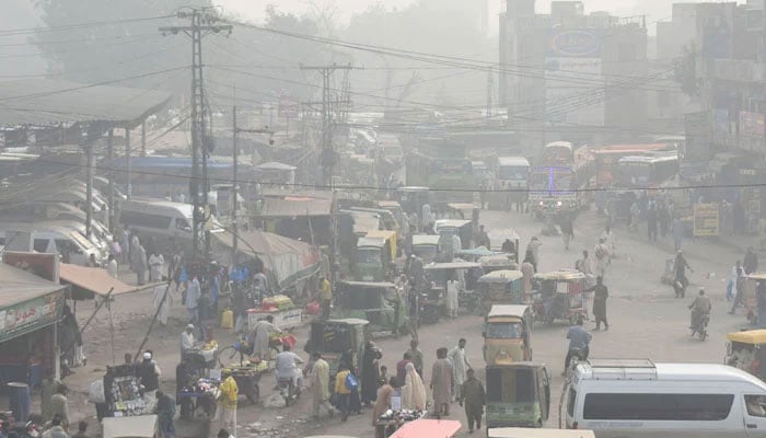 Commuters make their way amid heavy smog along a road, in Lahore. — Online/File