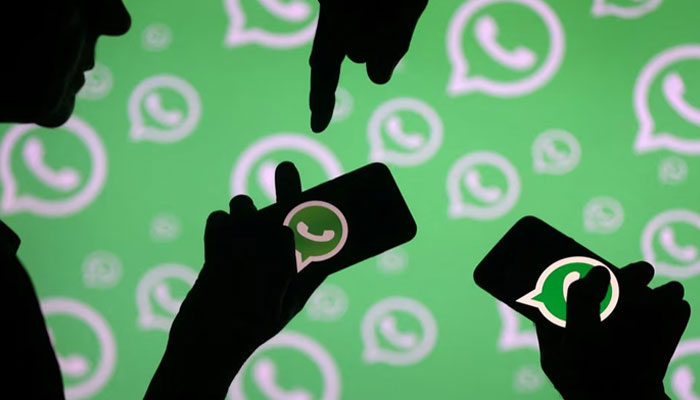 Men pose with smartphones in front of the displayed Whatsapp logo in this illustration on September 14, 2017.—Reuters