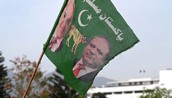 A supporter of PML-N holds a party flag with images of Shehbaz Sharif and his elder brother and three-time prime minister Nawaz Sharif outside the Parliament House in Islamabad on April 11, 2022. — AFP