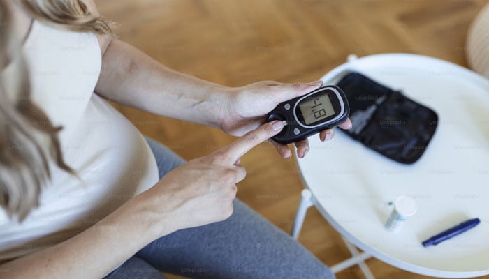 A pregnant woman checks her blood sugar levels at home on a glucometer. — Unsplash/File