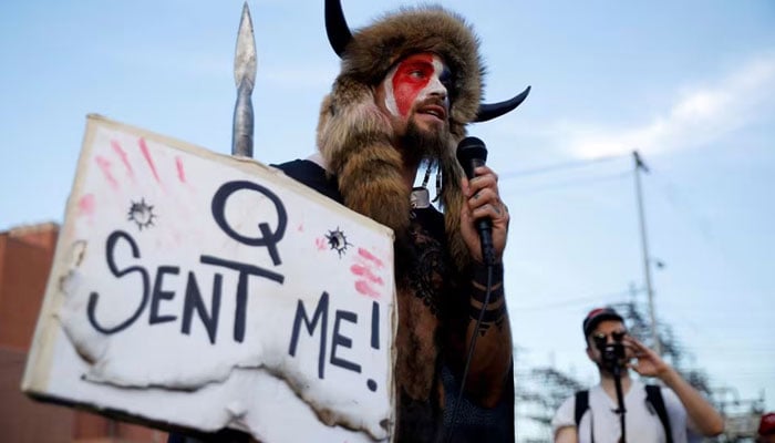 Jacob Chansley, holding a sign reading QAnon.—Reuters