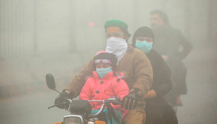 People use face masks to protect themselves from morning smog as they ride on bike along a road in Lahore, Pakistan November 10, 2017. — Reuters