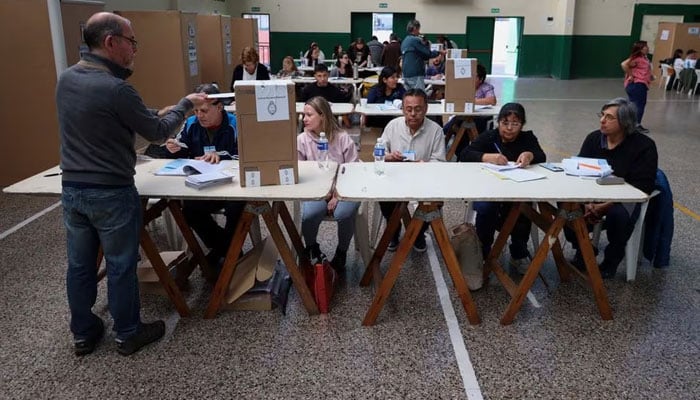 A man casts his vote next to electoral workers at a polling station during Argentinas runoff presidential election, in Buenos Aires, Argentina November 19, 2023.—Reuters