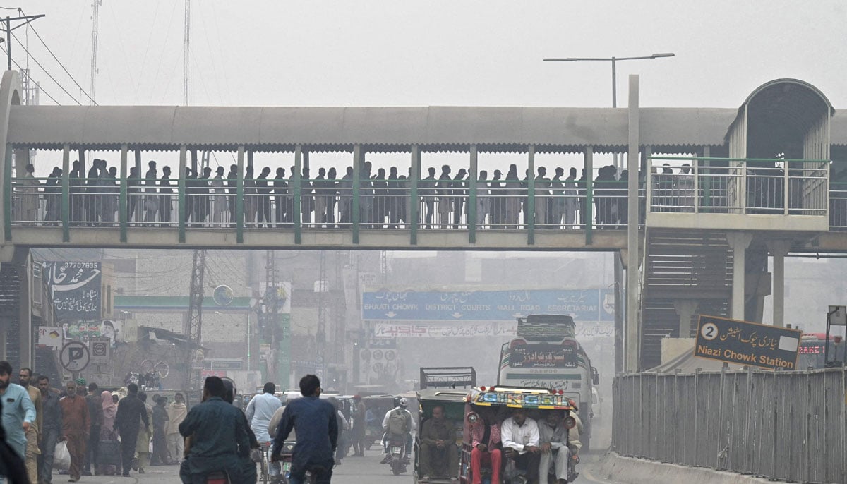 Commuters make their way through a busy street amid smoggy conditions in Lahore on November 7, 2023. — AFP