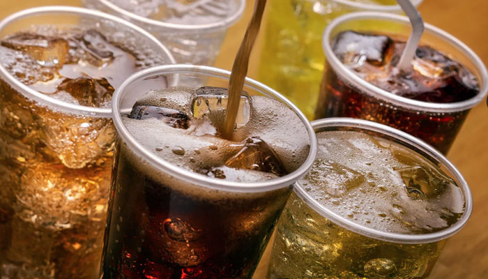 Variety of carbonated soft drinks in plastic cups with ice and straws.—Brittanica/file