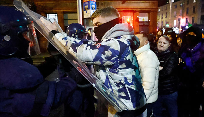 A man pushes the shield of an officer from riot police, near the scene of a suspected stabbing that left few children injured in Dublin, Ireland on November 23, 2023. — Reuters