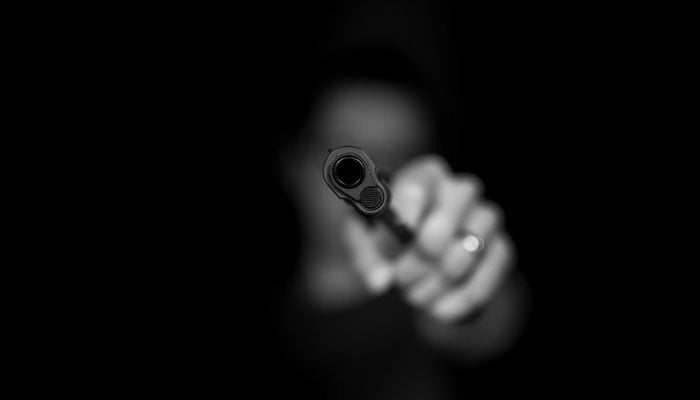 A representational image of a gun being held with the intention to fire. — Unsplash