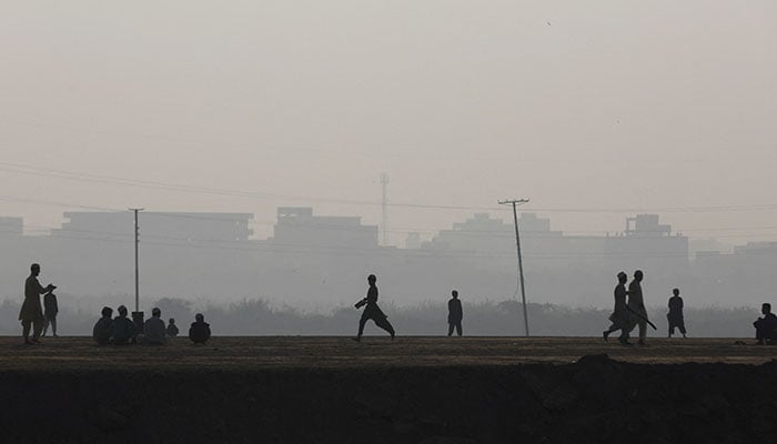 Children are silhouetted as they play cricket amid smog, as air pollution levels rise in Karachi on November 10, 2023. — Reuters