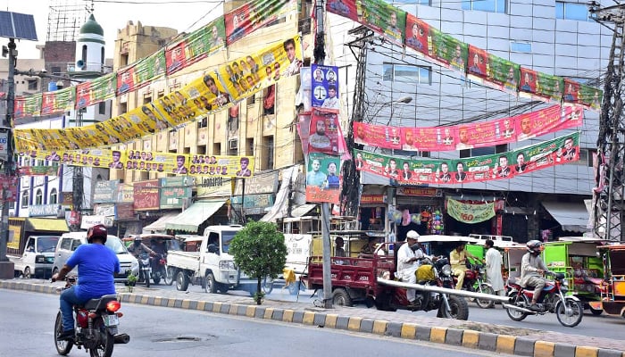 Different political parties’ flags and banners hanging on wires at a road in Lahore, on July 2, 2023. — APP