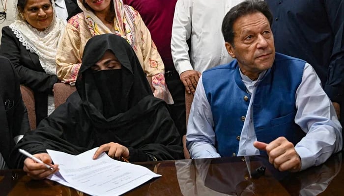 Former prime minister Imran Khan (right) along with his wife Bushra Bibi (centre) signs surety bonds for bail in various cases, at the registrars office in the Lahore High Court on July 17, 2023. — AFP