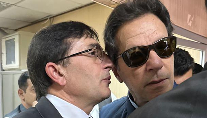 PTI leader Barrister Gohar Khan (left) whispers in PTI Chairman Imran Khans ear during his appearance before a court in this undated image. — X/@BarristerGohar