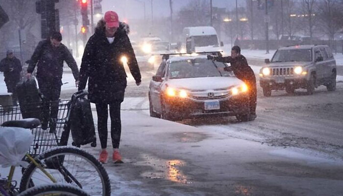 Pedestrians navigate a snow-covered sidewalk as temperatures hang in the single-digits on December 22, 2022 in Chicago, Illinois. — AFP