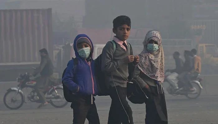 Children walk to school amid heavy smog conditions in Lahore on December 1, 2022. — AFP