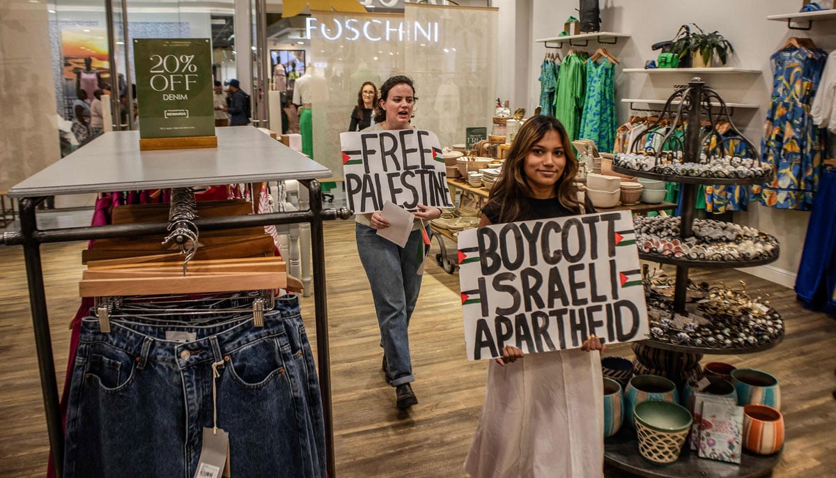 South African activists of the Boycott, Divestment and Sanctions (BDS) hold banners with slogans in support of the Palestinian territories inside a shop as they take part in a picket at the Rosebank Mall in Johannesburg against the South African retail chain Cape Union Mart during a nationwide action on November 18, 2023. — AFP