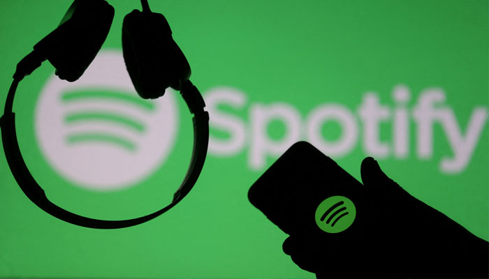 A smartphone and a headset are seen in front of a screen projection of Spotify logo, in this picture illustration taken April 1, 2018..—Reuters