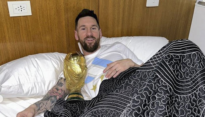 In this handout picture posted on the official Instagram account of @leomessi, Argentina´s captain and forward Lionel Messi poses in bed with the FIFA World Cup Trophy at the Argentine Football Association (AFA) training centre in Ezeiza, Buenos Aires province, Argentina, on December 20, 2022. — AFP