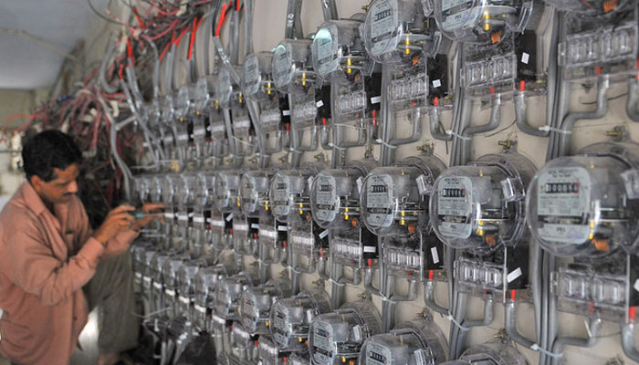 A technician fixes new electricity meters at a residential building in Karachi, Pakistan, on May 13, 2010. — AFP