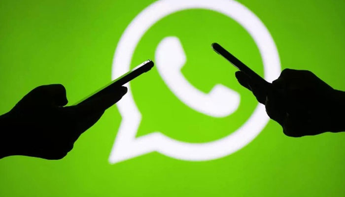 Silhouettes of two peoples hands holding smart phones seen in front of WhatsApp logo lightened up on a screen. — AFP/File