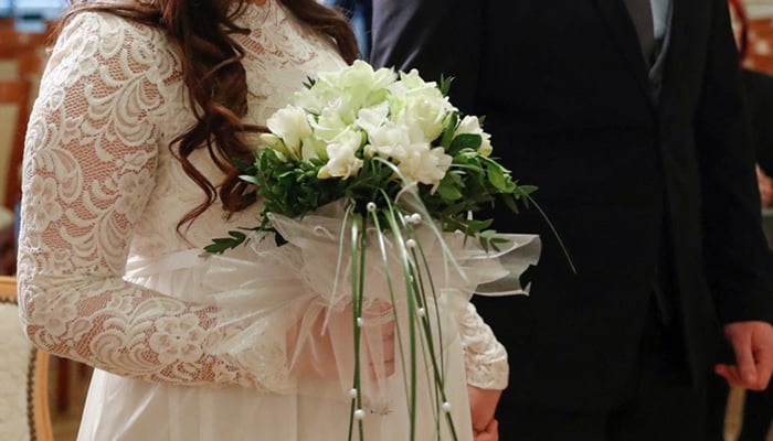 A bride holds a bouquet in her hand at a marriage. — Reuters
