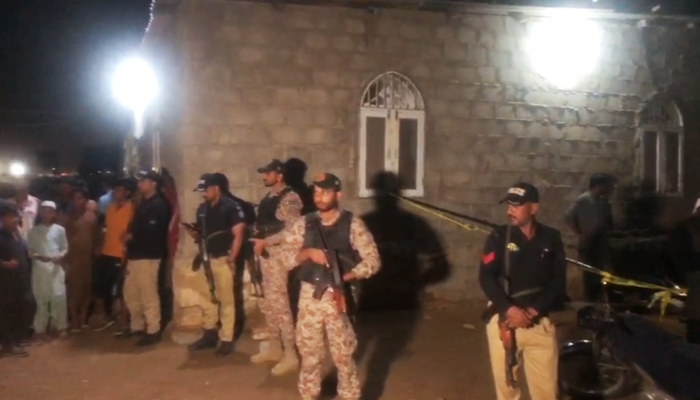Police and Rangers personnel stand guard near the crime scene in Karachis Machar Colony, on December 11, 2023, in this still taken from a video. — Reporter
