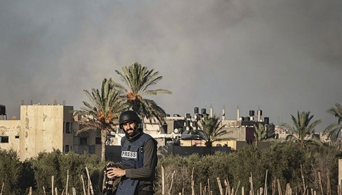 Motaz is seen in a press vest with smoke rising in his background due to Israeli airstrikes. — Instagram/@motaz_azaiza