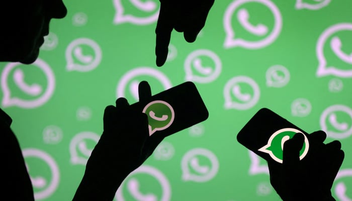 Men pose with smartphones in front of displayed Whatsapp logo in this illustration. — Reuters/File