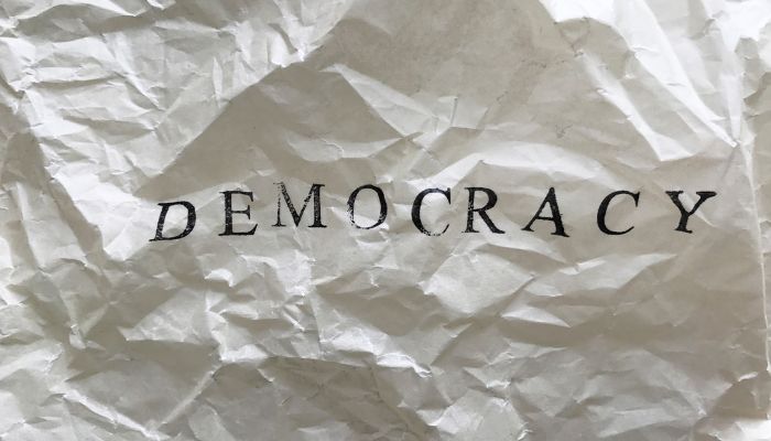 The picture shows a crumpled paper with democracy written on it. — Canva