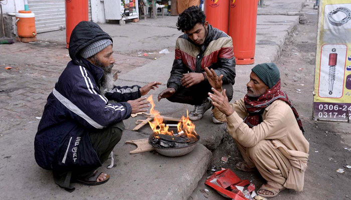 People warm their hands by burning wood fire during the winter season in Lahores Old Anarkali on December 23, 2023. — APP
