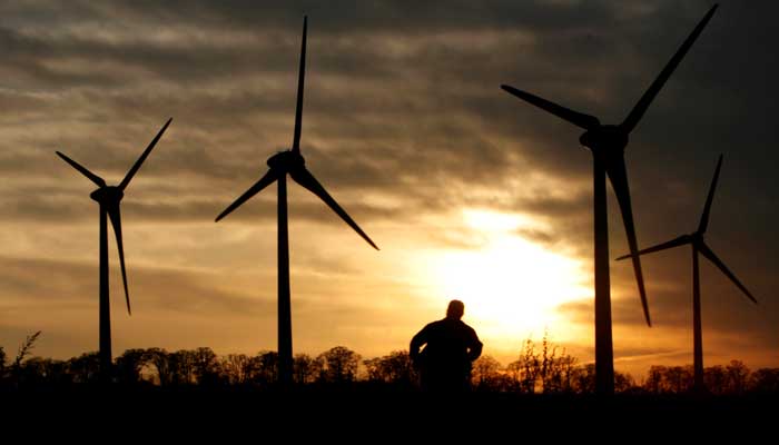 A man looks at 100-meter (328-foot) tall wind turbines during sunset at the Electric Power Development Co., Ltds Nunobiki Plateau wind farm in Koriyama, north of Tokyo, Japan, November 8, 2007. — Reuters