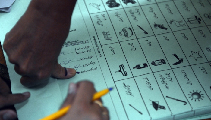 A Pakistani voter presses inked thumb onto a ballot paper before casting vote at a polling station in Islamabad on May 11, 2013. —AFP