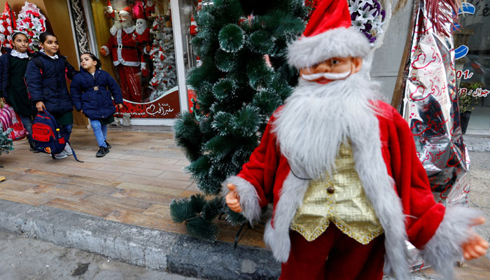 Palestinian schoolgirls walk past a shop selling Santa Claus costumes in Gaza City, on December 22, 2022. —Reuters