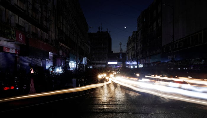 Vehicle lights cause light streaks on the road along a market, during a country-wide power breakdown in Karachi, on January 23, 2023. — Reuters