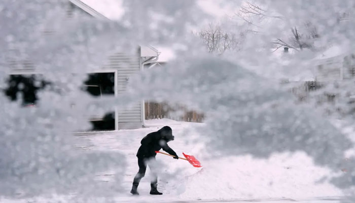 A resident of Urbandale, Iowa, shovels snow off the end of a driveway after temperatures quickly plunged on December 22, 2022, as a winter storm swept across the Midwest. — AFP