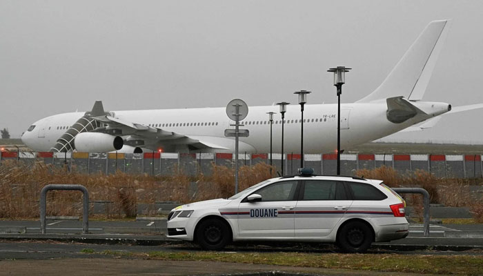A French customs car with the grounded Airbus A340 in the background at Vatry airport in France. The plane was kept on the tarmac for four days over suspected human trafficking. — AFP
