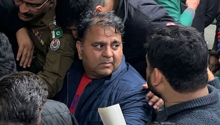 Police officials escort former federal minister Fawad Chaudhry to present him before a court in Lahore on January 25, 2023. — AFP