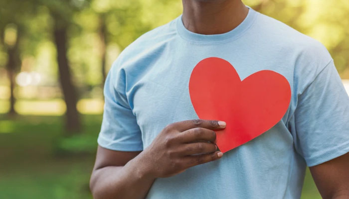 A person holding a heart card while standing in a garden. — X/thekey