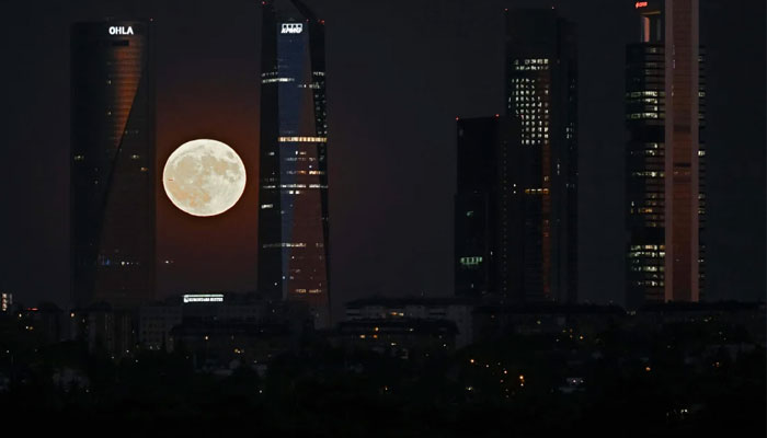 A supermoon can be seen rising over the Cuatro Torres business area in Madrid on August 1, 2023.-AFP
