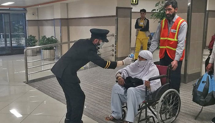 An airport official checks the temperature of a passenger upon his arrival at the Bacha Khan International Airport in Peshawar on January 27, 2020. — AFP