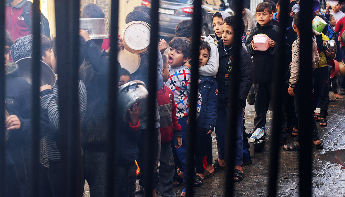 Palestinian children carry pots as they queue to receive food cooked by a charity kitchen, amid shortages in food supplies, as the conflict between Israel and Hamas continues, in Rafah in the southern Gaza Strip December 14, 2023. — Reuters