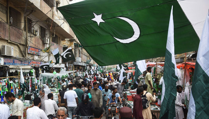 People thorong a market where vendors sell Pakistan´s national flags in Karachi on August 11, 2023, ahead of the country´s 76th Independence Day. — AFP