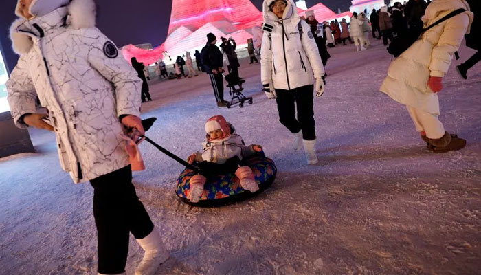 A visitor pulls a tire with a child sitting on it at the Harbin International Ice and Snow Festival, in Harbin, Heilongjiang province, China January 4, 2024. — Reuters